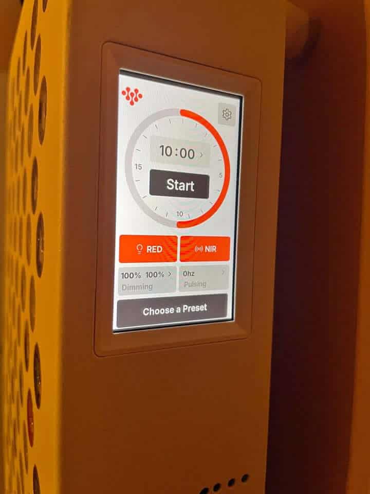 A person using an Infraredi panel for full body red light therapy.