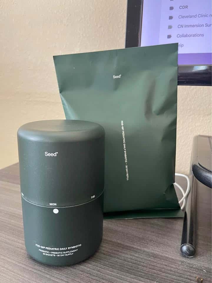 Seed PDS-08 synbiotic powder shown with fresh fruit, illustrating its natural formulation.