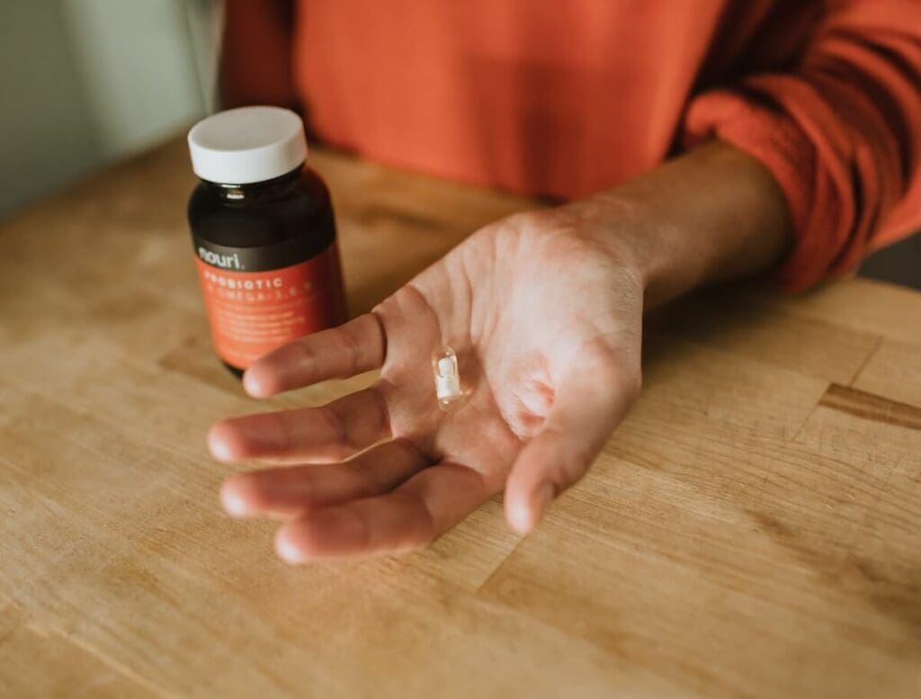 A person holding a bottle of probiotic supplement with a label showing 10 different probiotic strains