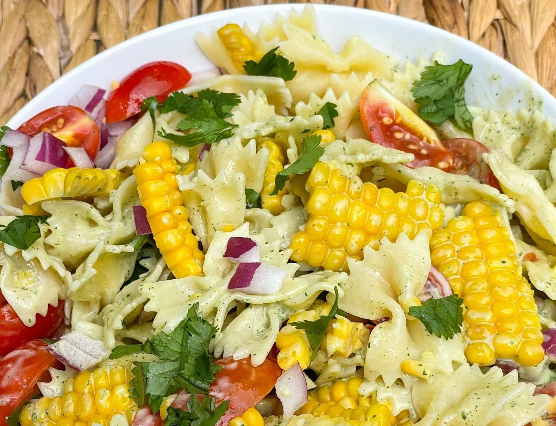 a bowl of pasta salad with corn and tomatoes