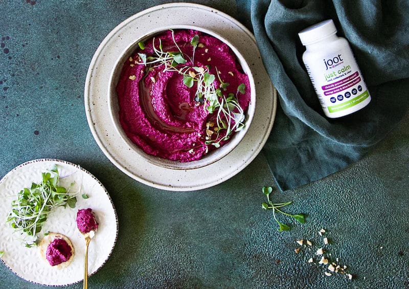 a bowl of hummus and a bottle of vitamins