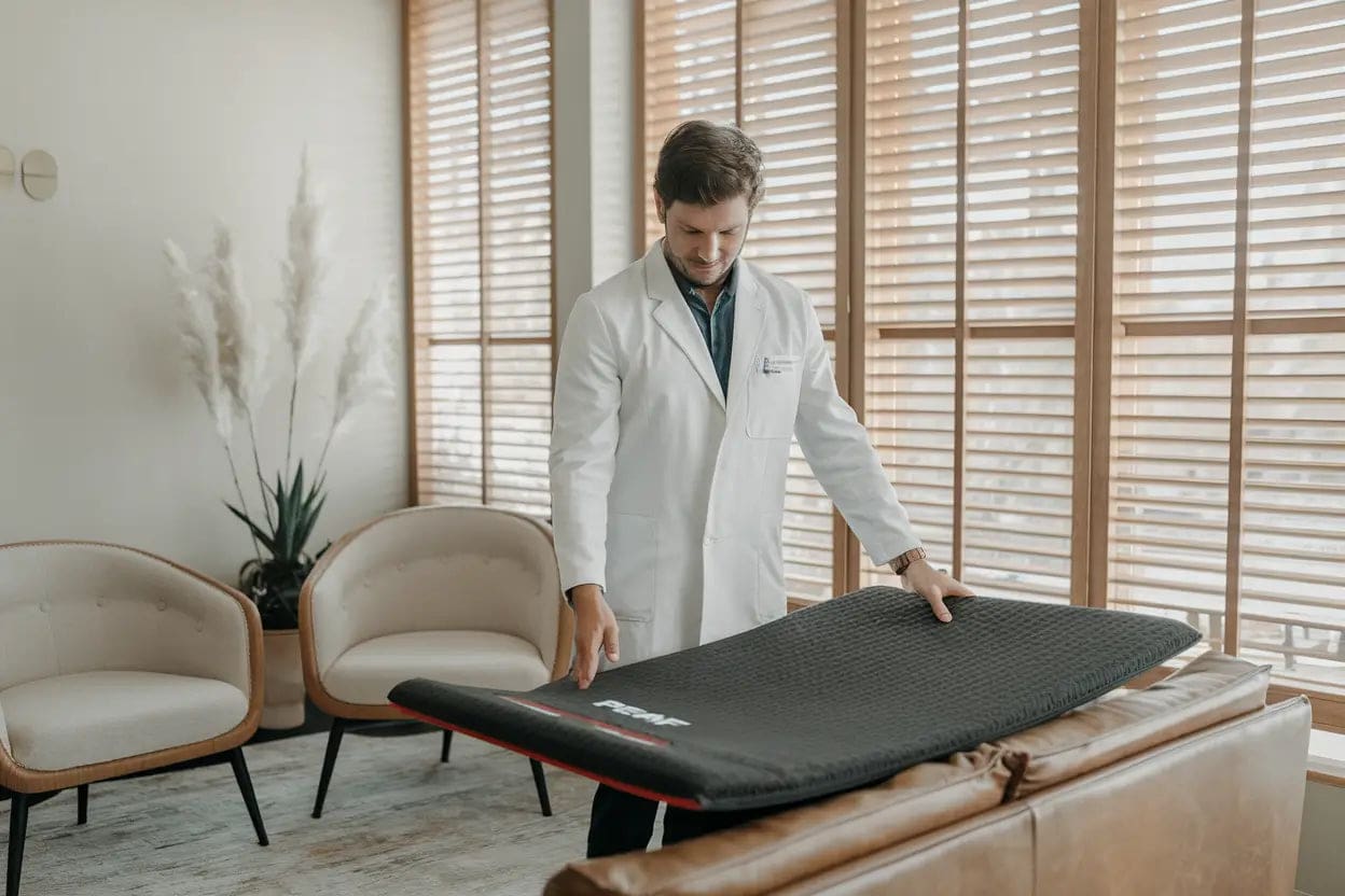 A serene setting with a person lying on a PEMF therapy mat surrounded by soft lighting and a calming atmosphere